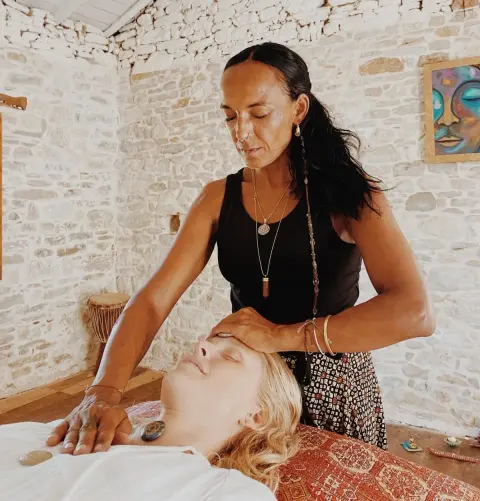 Reiki-Behandlung in einem hellen Raum, Hände am Kopf einer liegenden Frau.