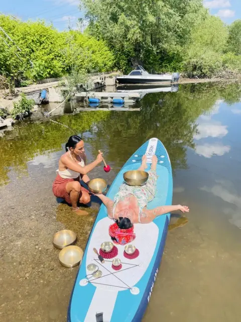 Klangmassage auf einem Paddle-Board auf dem Wasser.