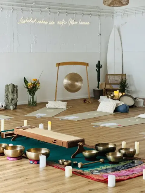Ein heller Raum mit Gong und Klangschalen, vorbereitet für eine Gruppe.