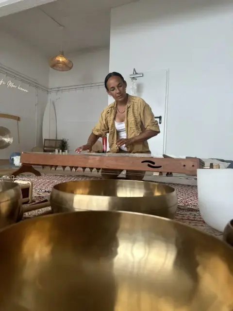 Dunja spielt große Klangschalen in einem hellen Raum.