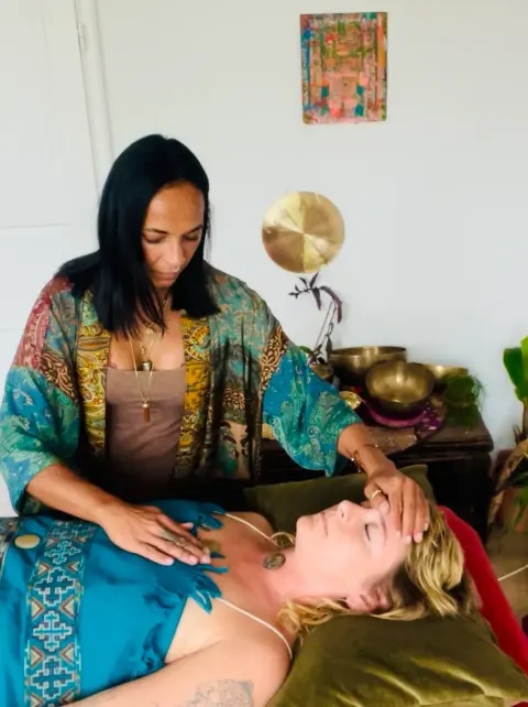Reiki-Behandlung: Hände liegen sanft am Kopf einer liegenden Frau.