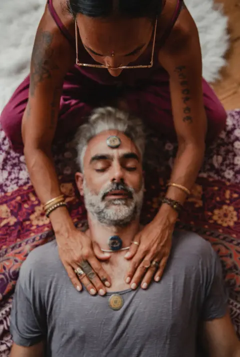 Reiki-Behandlung an einem liegenden Mann, die Hände liegen auf seinen Schultern.