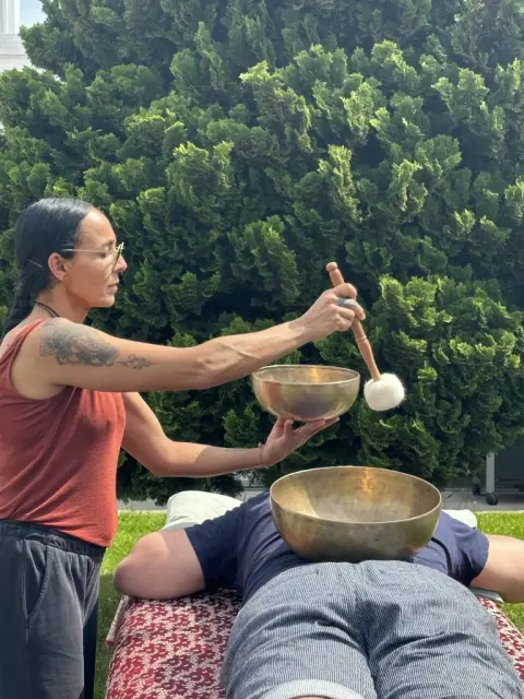 Klangmassage im Grünen, eine Klangschale steht auf dem Körper.